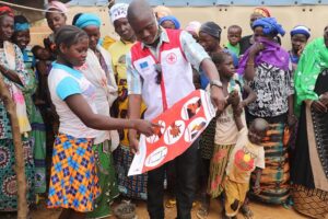 A volunteer shares information from a poster with community members in Burkina Faso